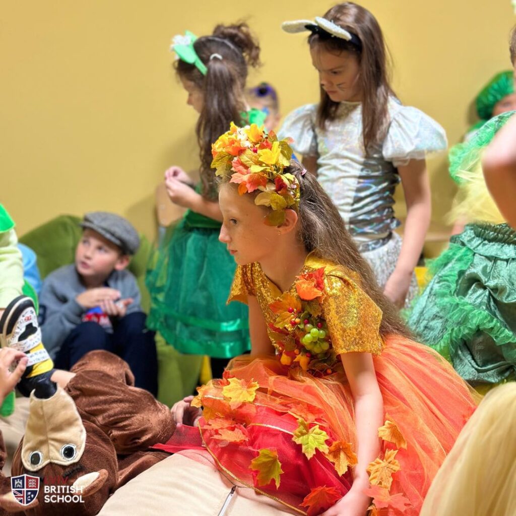 A girl in a costume of autumn - very vibrant with yellow, orange and red leaves on it
